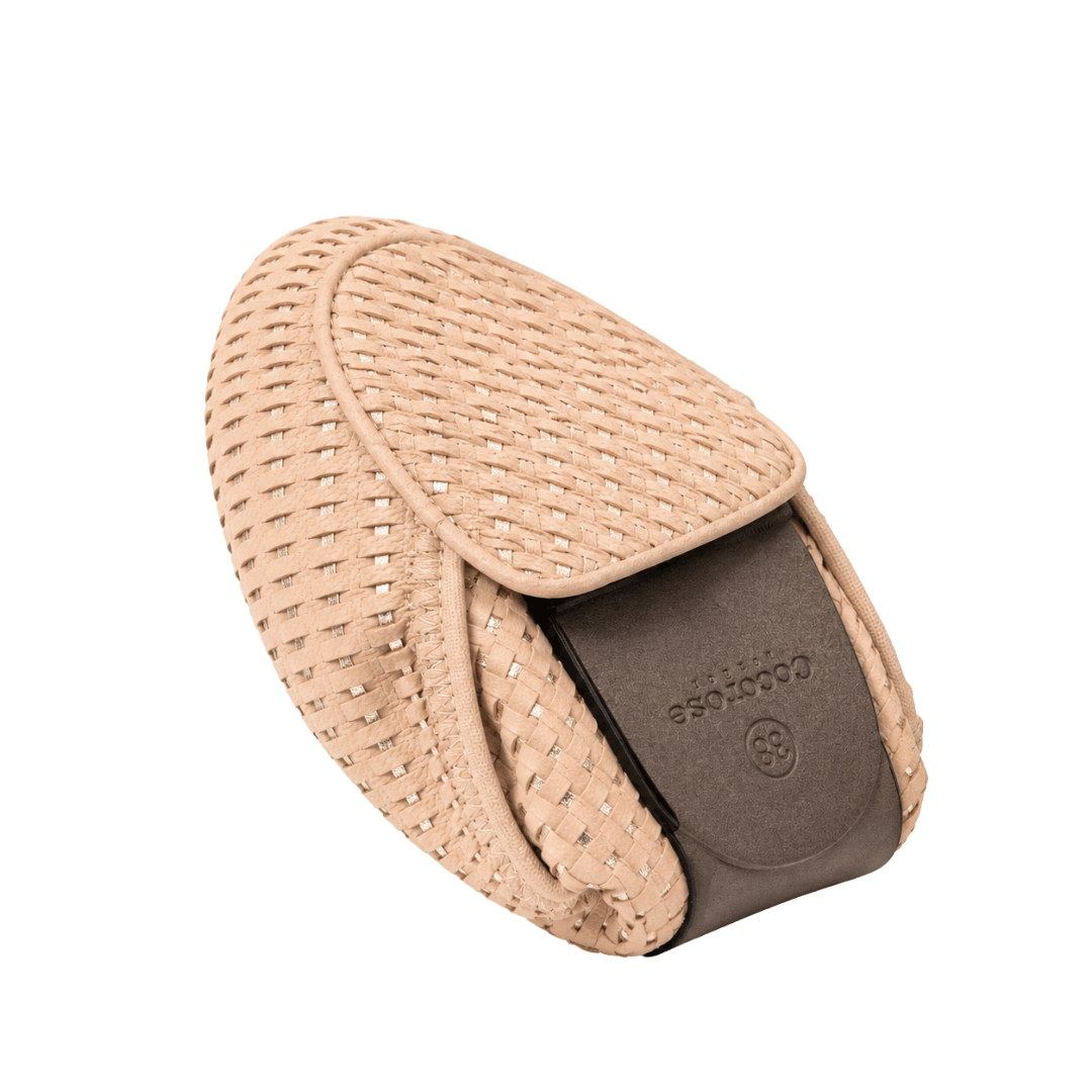 A single beige woven loafer completely folded in half, displaying its flexible design and dark brown sole with a embossed logo against a white background.