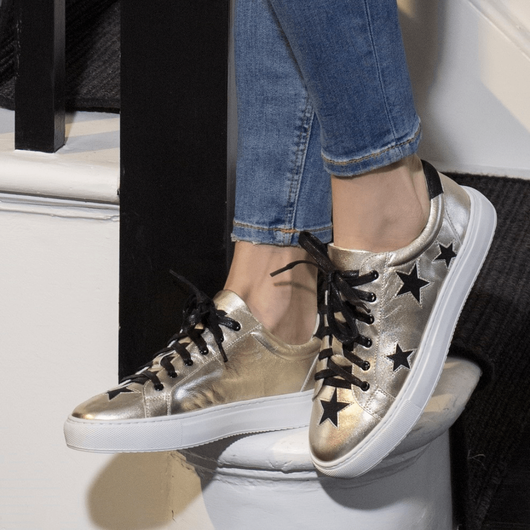 Hoxton gold leather trainers with black stars styled with skinny jeans