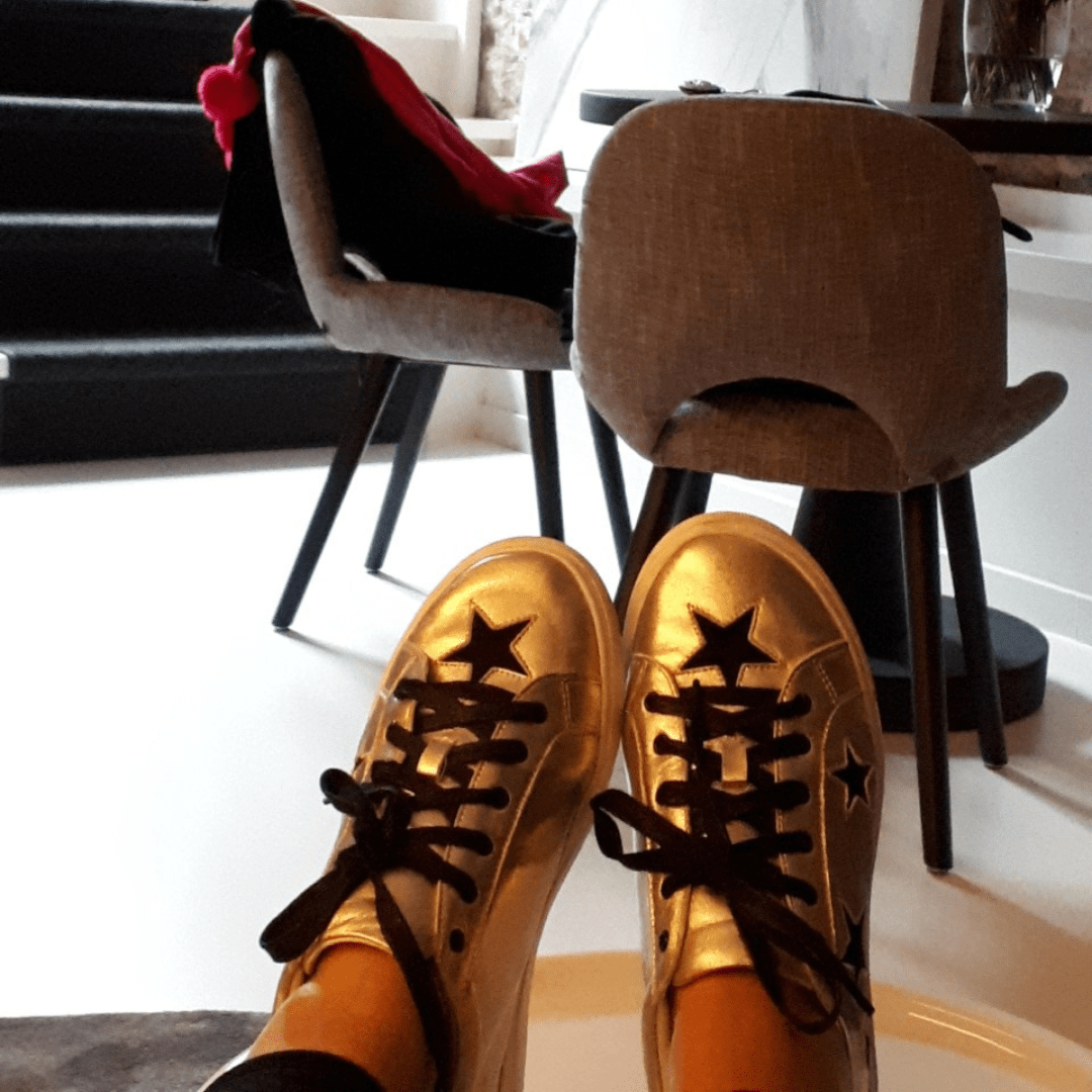 relaxed at home wearing gold leather trainers with black stars