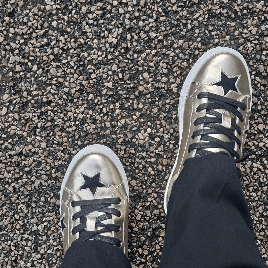 close-up of gold leather trainers with black stars, comfortable everyday trainers for women