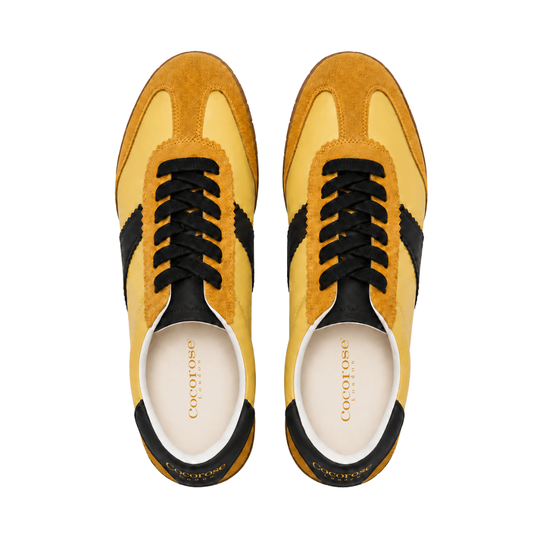 Yellow leather and suede sneakers with chocolate brown accents on a white background