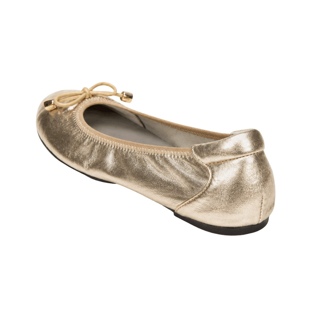 An angled three-quarter rear view of a single metallic gold ballet flat against a white background, highlighting its structured heel counter, elasticated trim, and a small bow detail at the toe.