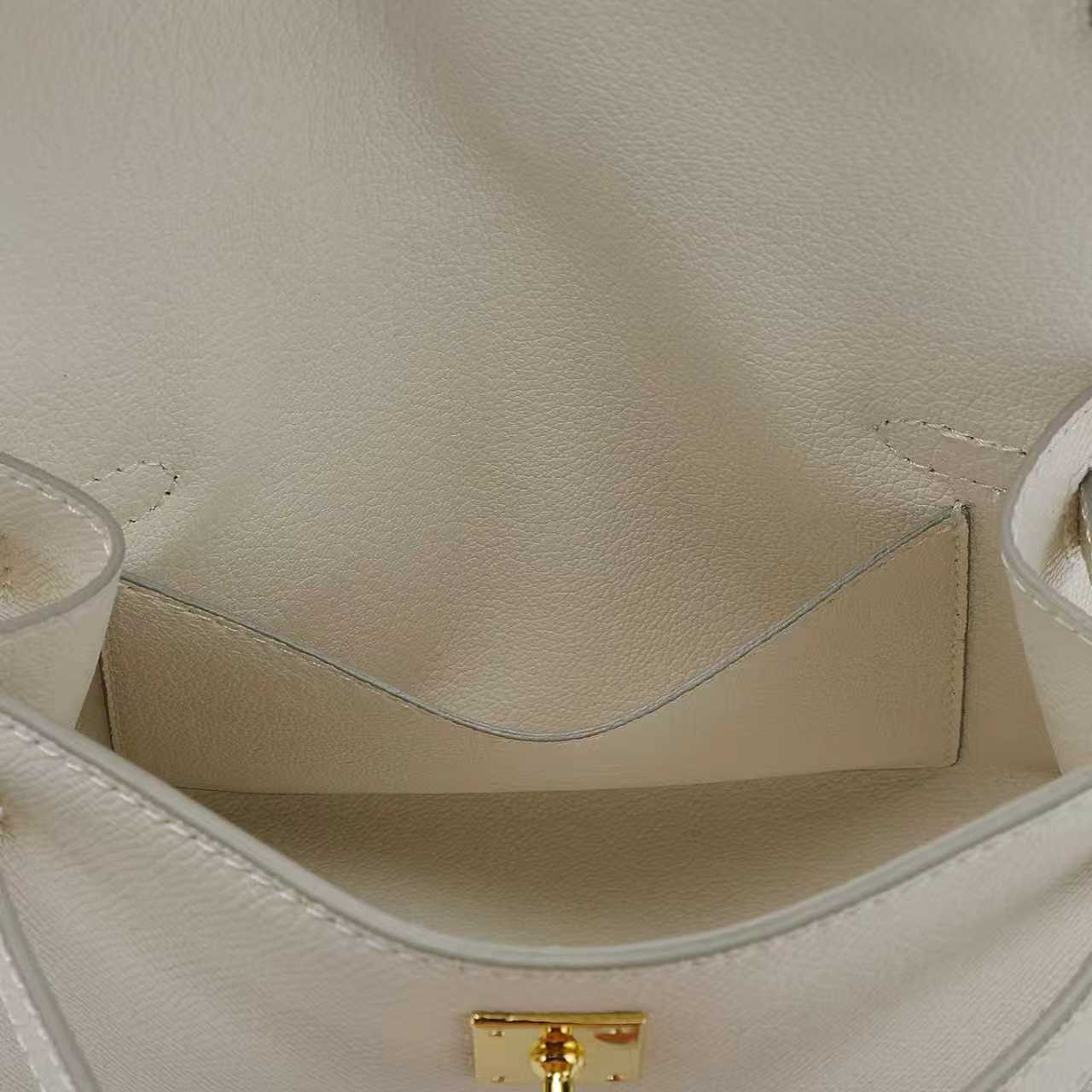 Close-up of the inside compartment including inner pocket of a white leather handbag with a gold clasp