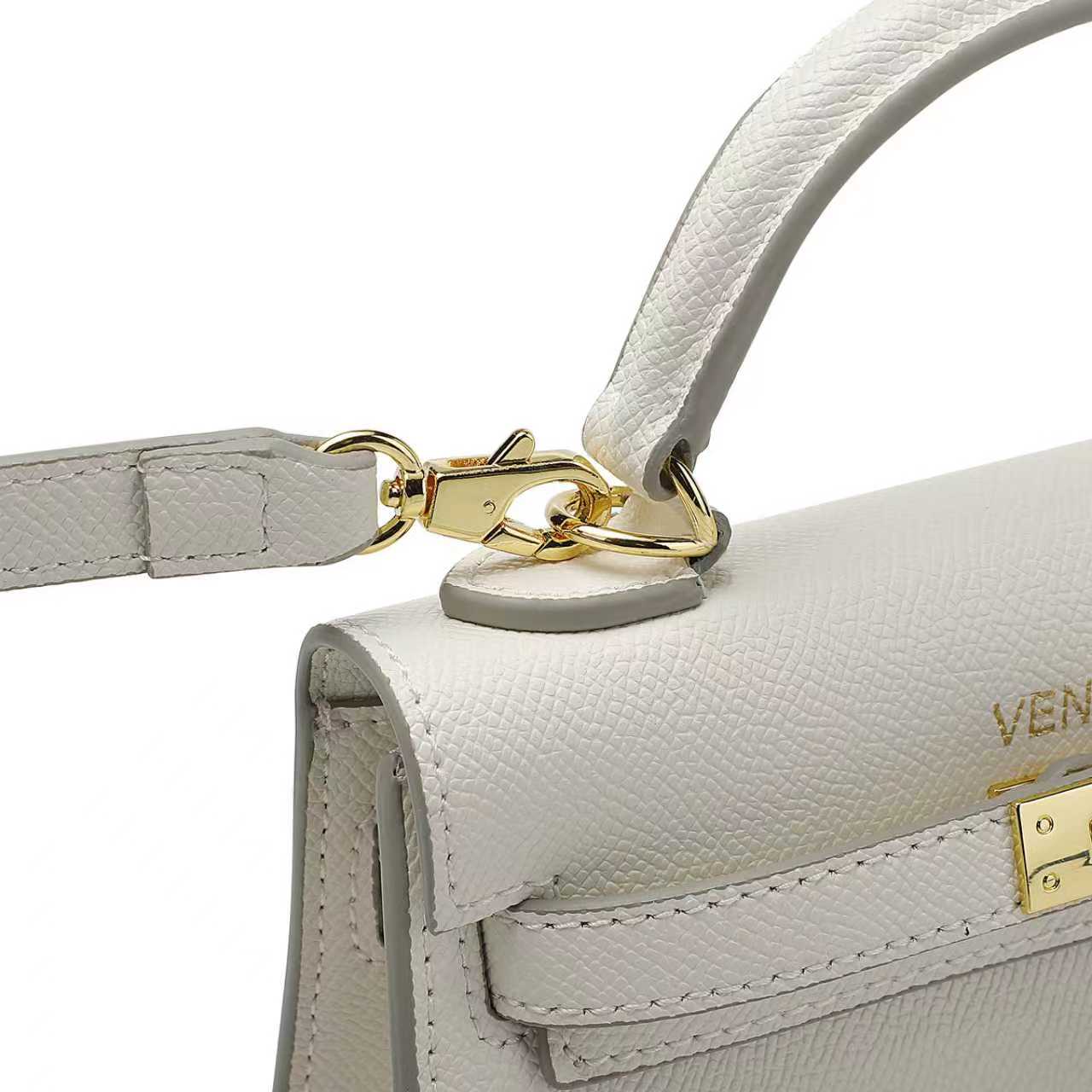 Close-up of a white leather handbag with a detachable gold clasp and shoulder strap on a white background
