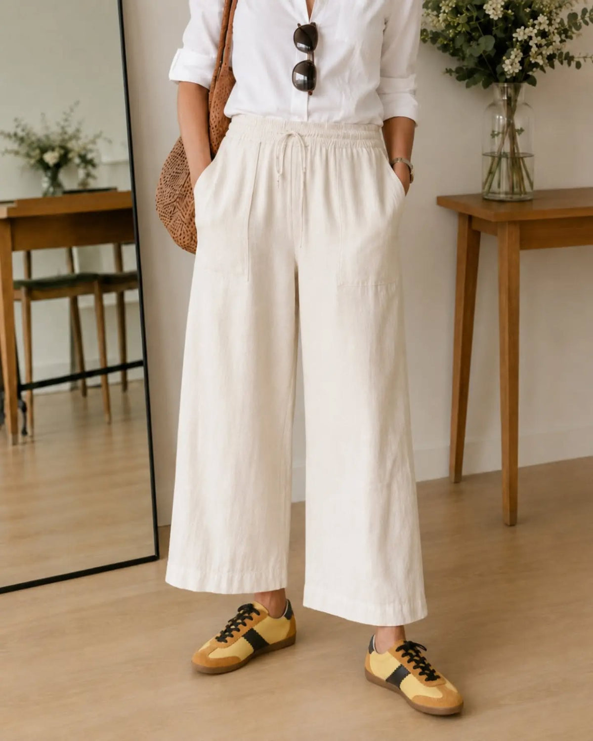Women in wide leg white trousers, with white shirt, and Cocorose Yellow leather trainers - heading to a job interview