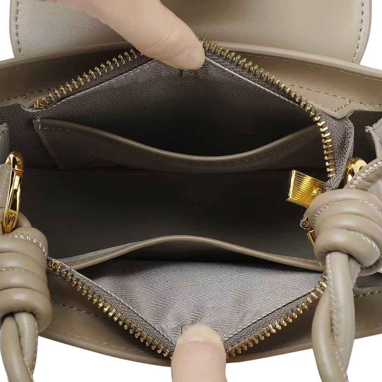 Close-up of a beige handbag with gold zipper and handle details.