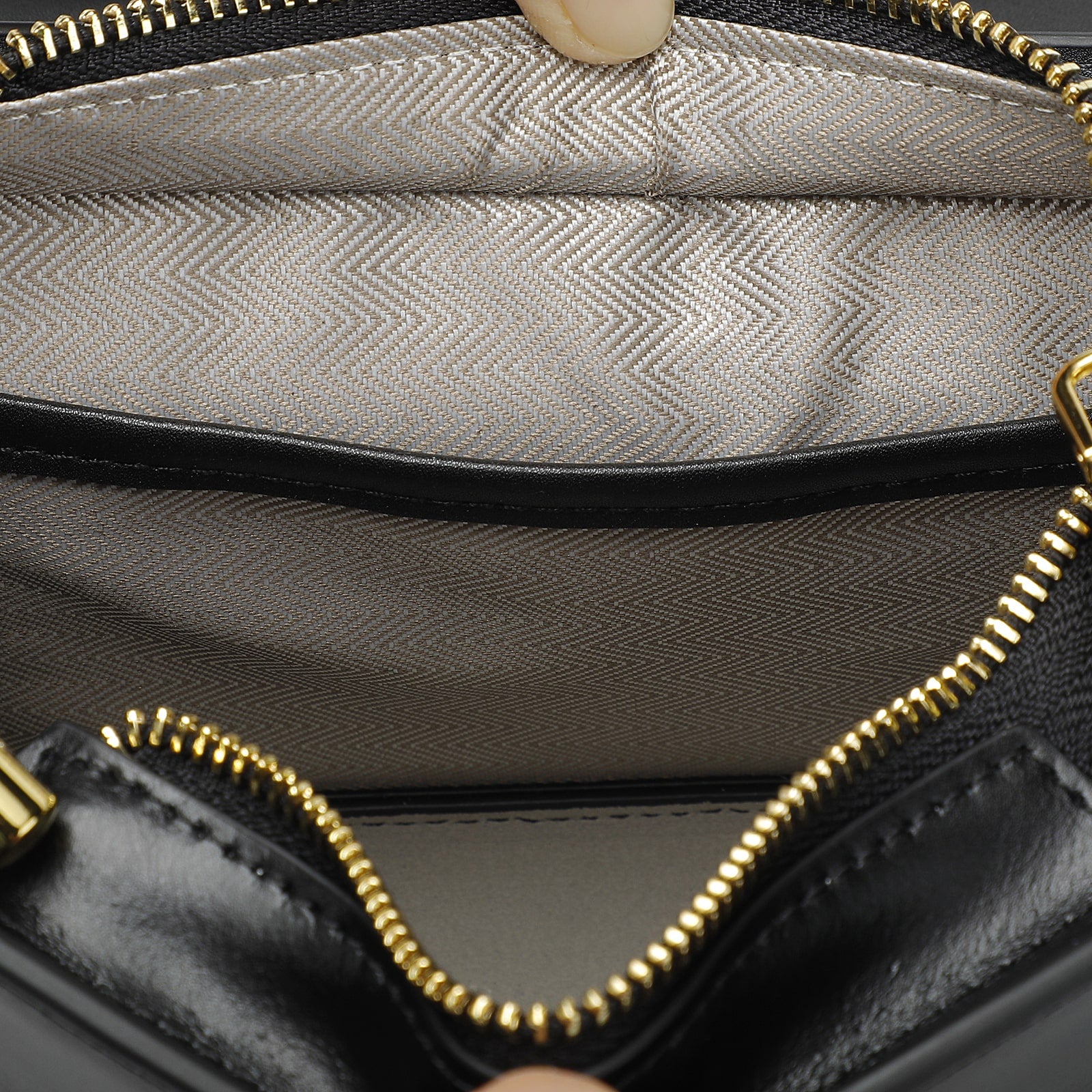 Close-up of a black handbag with gold zipper and textured interior.