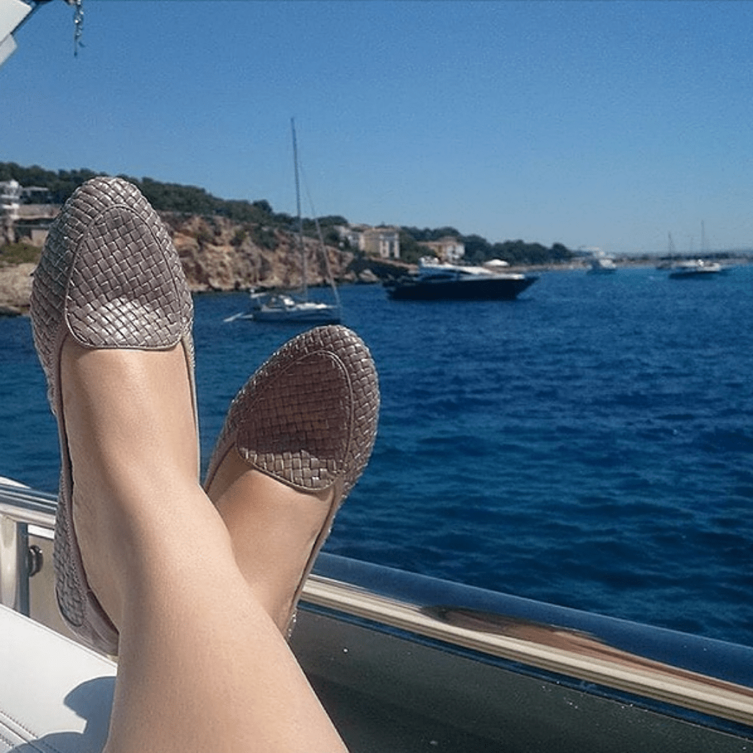 Dusky pink loafers against a beach background
