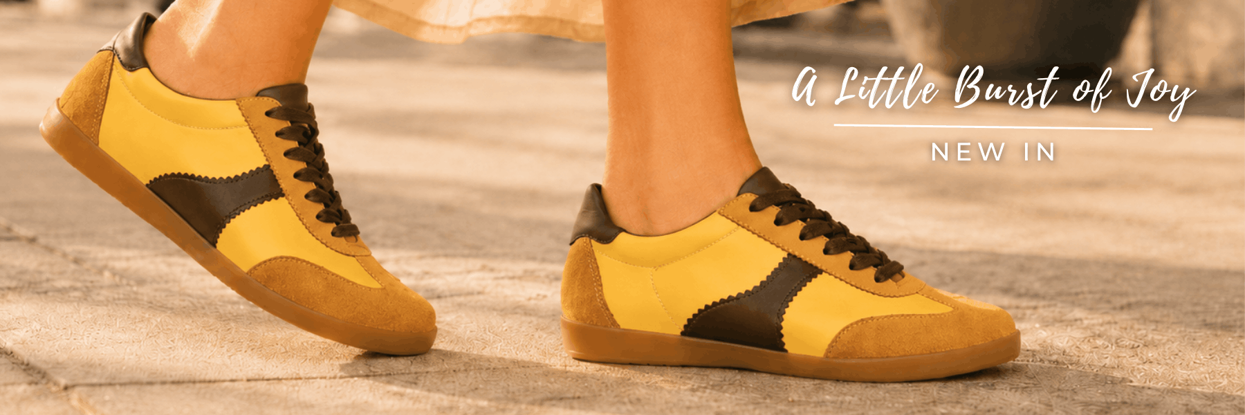 Close-up of a person walking in Moorgate yellow and chocolate brown leather trainers, featuring promotional text that reads "A Little Burst of Joy, NEW IN"
