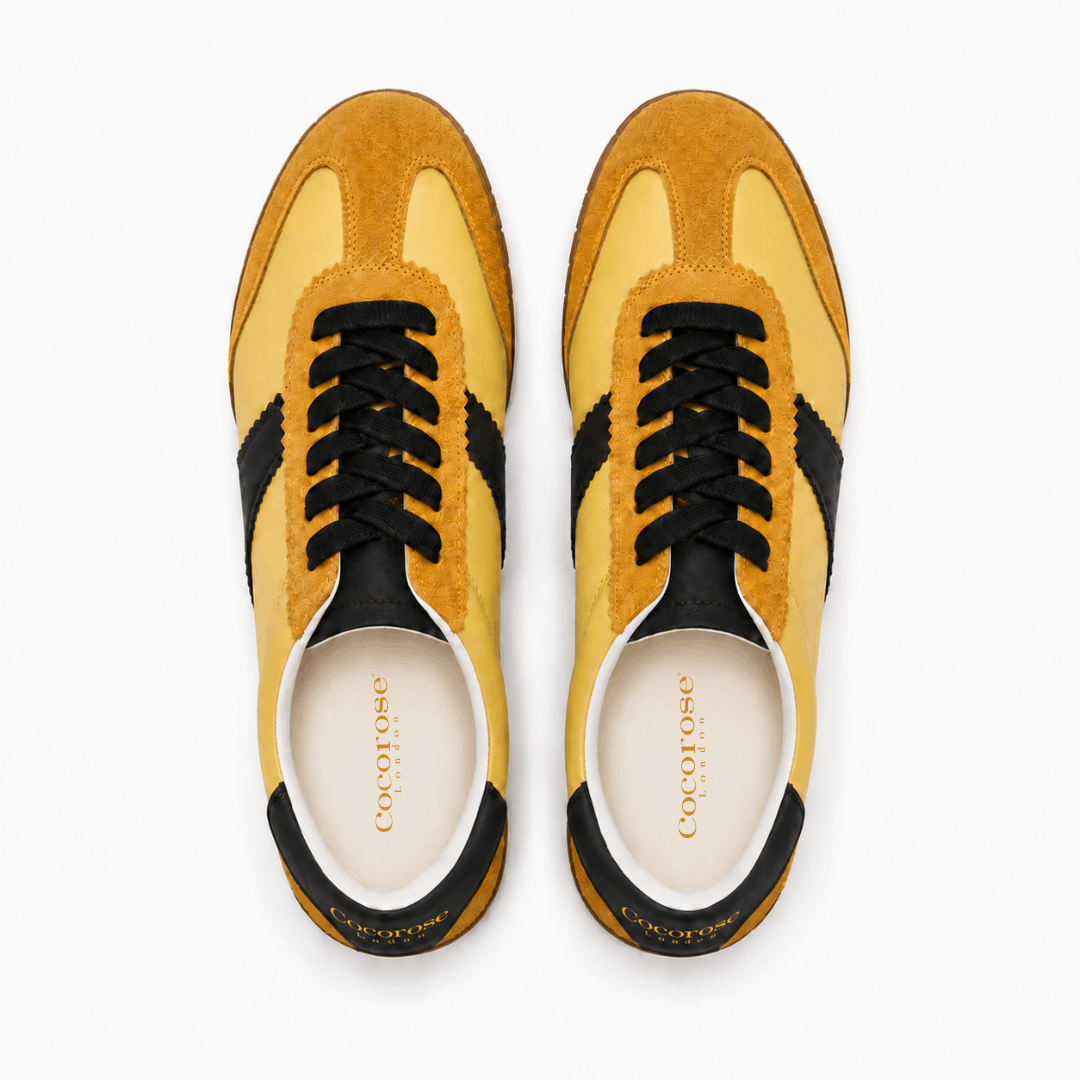 Pair of yellow and chocolate brown  leather sneakers on a white background