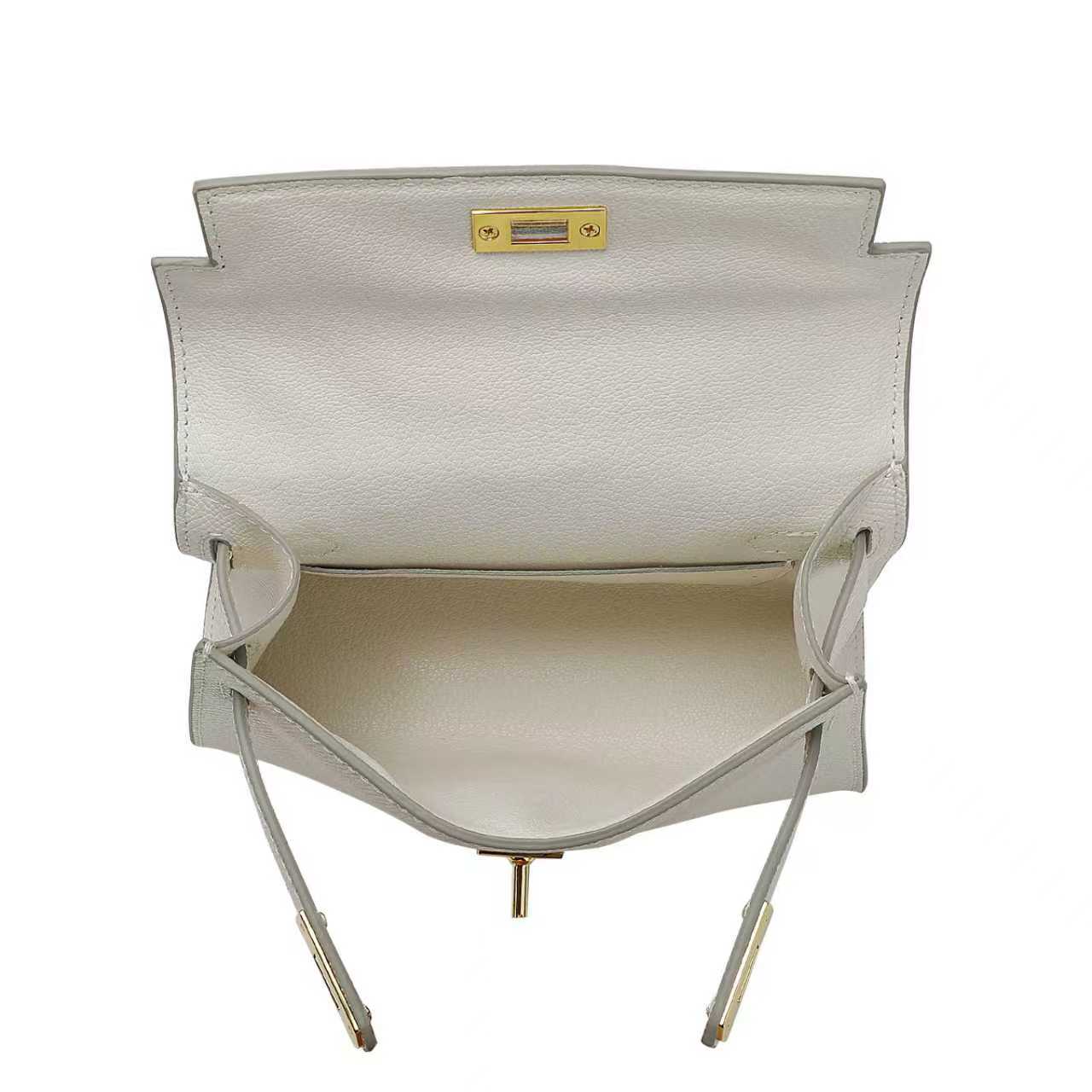 Inside compartment of a white leather handbag with gold clasp on a white background